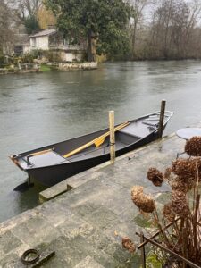 Barque amarrée quai fleuve, maisons anciennes arrière-plan.